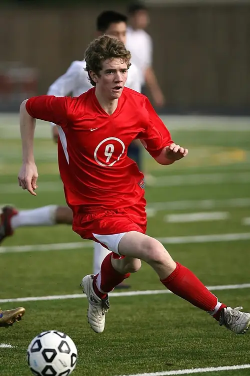 young male player playing football in red shirt